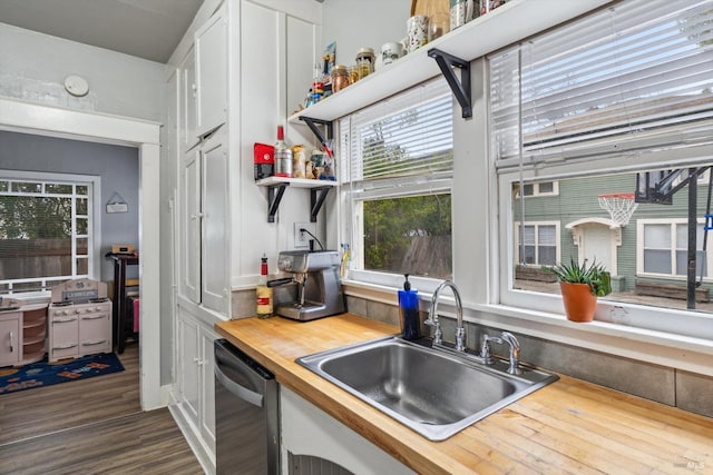 kitchen featuring white cabinetry, sink, wooden counters, stainless steel dishwasher, and dark wood-type flooring