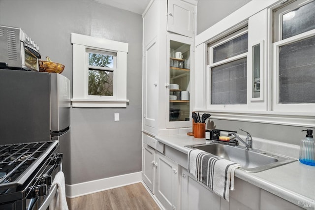 kitchen with sink, light hardwood / wood-style flooring, white cabinets, and appliances with stainless steel finishes