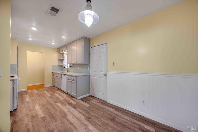 kitchen with white dishwasher, sink, gray cabinetry, and light wood-type flooring