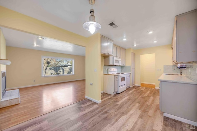 kitchen featuring tasteful backsplash, sink, white appliances, and light hardwood / wood-style floors