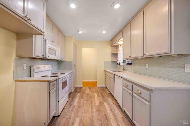 kitchen featuring white appliances, light hardwood / wood-style floors, sink, and backsplash