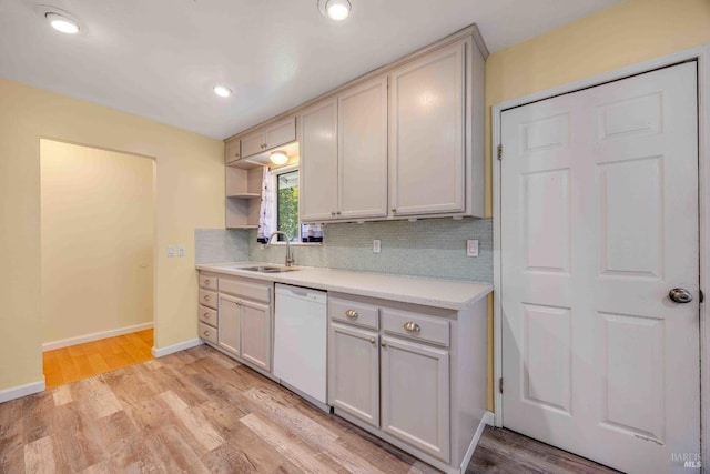 kitchen with dishwasher, sink, backsplash, and light wood-type flooring