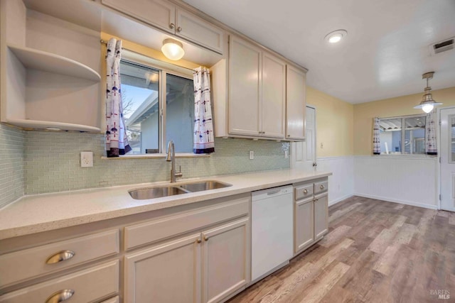 kitchen with sink, light wood-type flooring, dishwasher, pendant lighting, and decorative backsplash