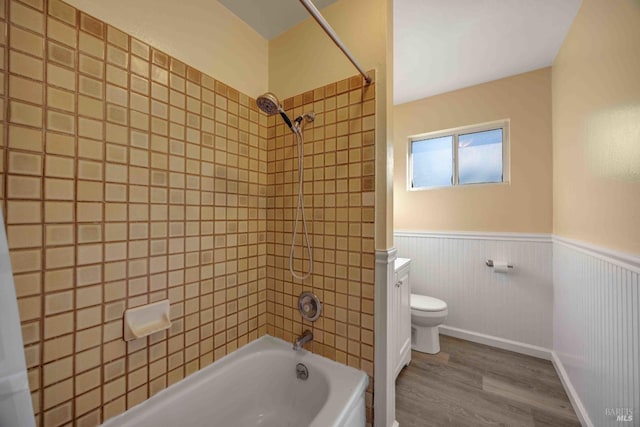 bathroom with toilet, tiled shower / bath combo, and hardwood / wood-style floors