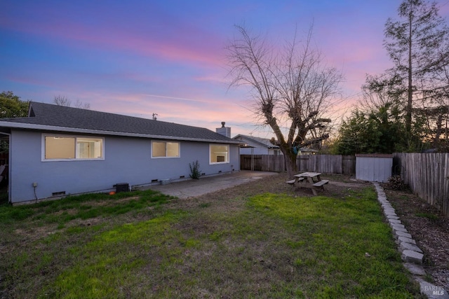 back house at dusk with a yard and a patio area