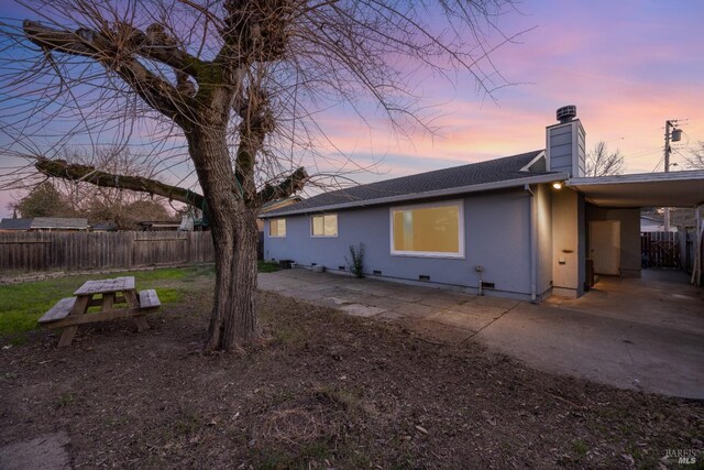 back house at dusk featuring a patio