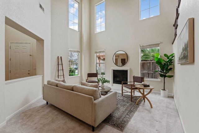 living room featuring carpet, visible vents, baseboards, and a glass covered fireplace