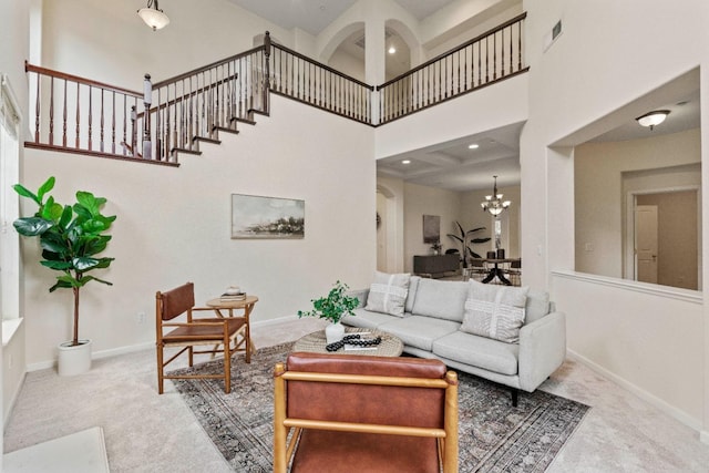 living area with a towering ceiling, a notable chandelier, visible vents, and carpet flooring