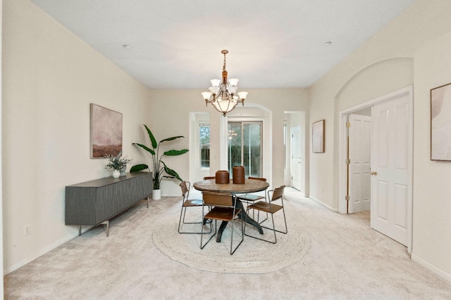 dining room with a notable chandelier, baseboards, and light colored carpet