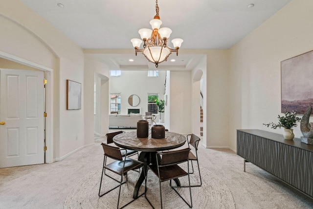 dining space featuring carpet floors, baseboards, arched walkways, and a chandelier