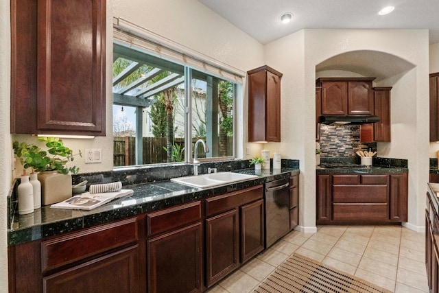 kitchen with under cabinet range hood, a sink, dishwasher, tasteful backsplash, and dark countertops