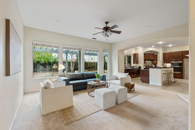 living room featuring light carpet, plenty of natural light, and arched walkways