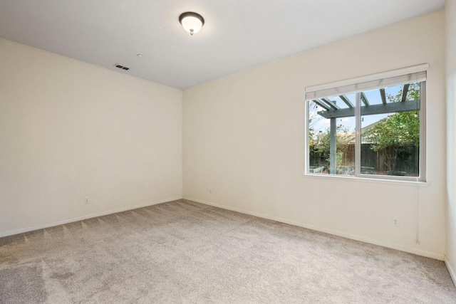 spare room with carpet, visible vents, and baseboards