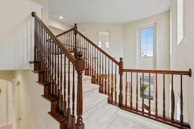 staircase with arched walkways and recessed lighting