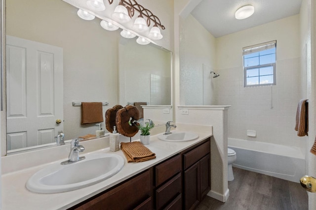 bathroom with double vanity, wood finished floors, a sink, and toilet