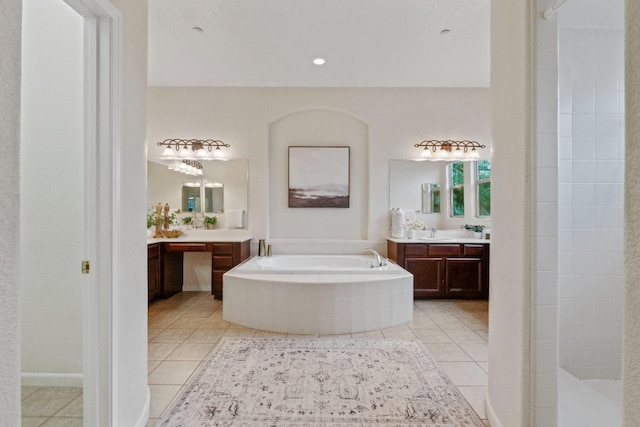 full bath with tile patterned floors, two vanities, tiled shower, and a bath