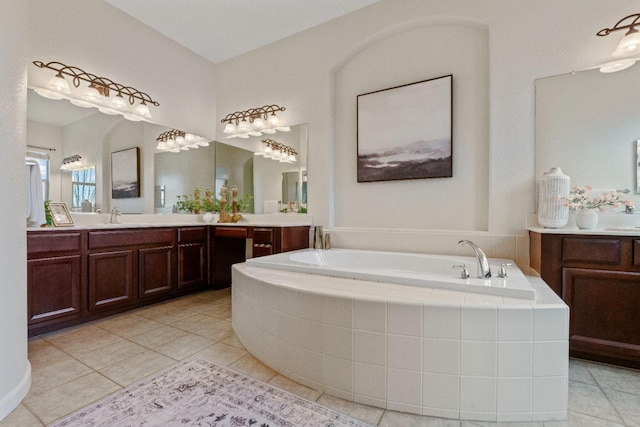 bathroom featuring tile patterned flooring, two vanities, a sink, and a bath