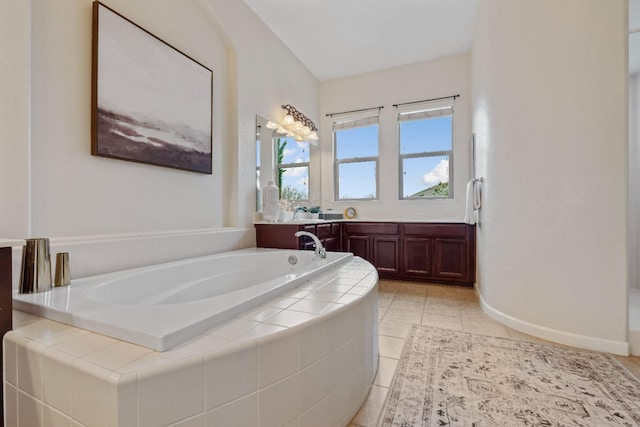 bathroom with tile patterned flooring, a garden tub, vanity, and baseboards