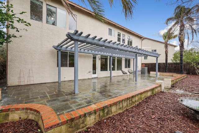 rear view of property featuring a patio area, fence, a pergola, and stucco siding