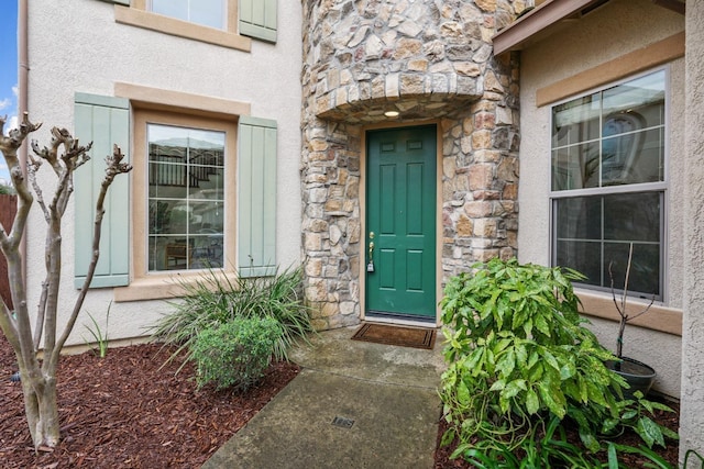 view of exterior entry featuring stone siding and stucco siding