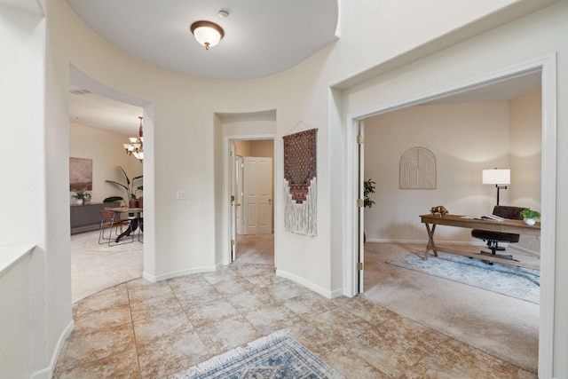 corridor with carpet, baseboards, and a notable chandelier