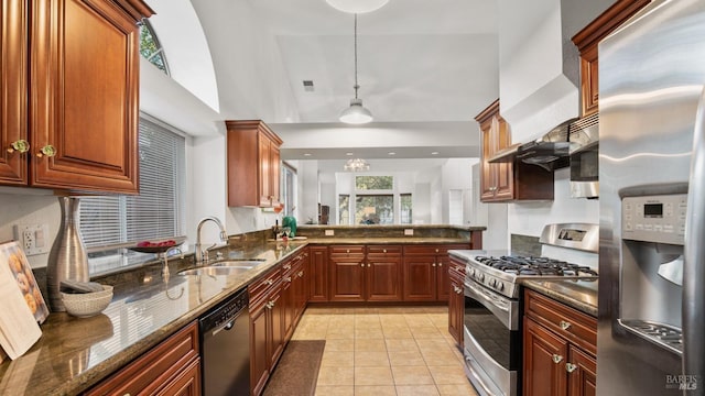 kitchen with light tile patterned floors, appliances with stainless steel finishes, dark stone countertops, decorative light fixtures, and a sink