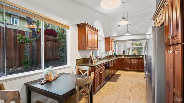 kitchen with brown cabinetry, freestanding refrigerator, light tile patterned flooring, a sink, and dishwasher