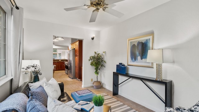 living area with light tile patterned flooring, ceiling fan, and baseboards