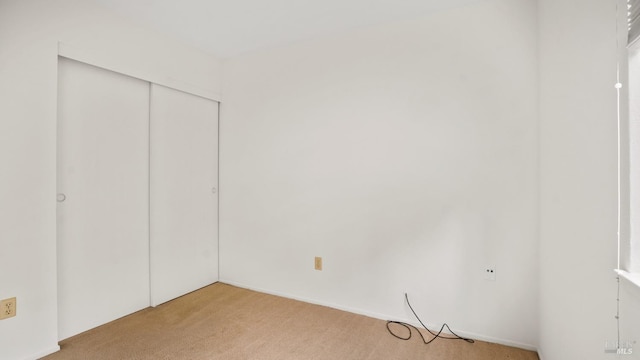 unfurnished bedroom featuring a closet and light colored carpet