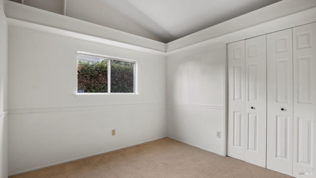 unfurnished bedroom with carpet floors, vaulted ceiling, and a closet