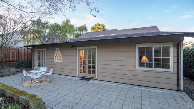 rear view of house featuring a shingled roof, fence, and a patio