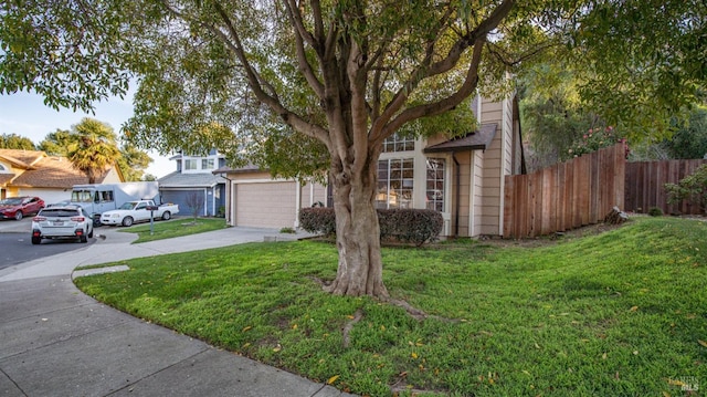 view of property hidden behind natural elements with fence, a front lawn, and concrete driveway