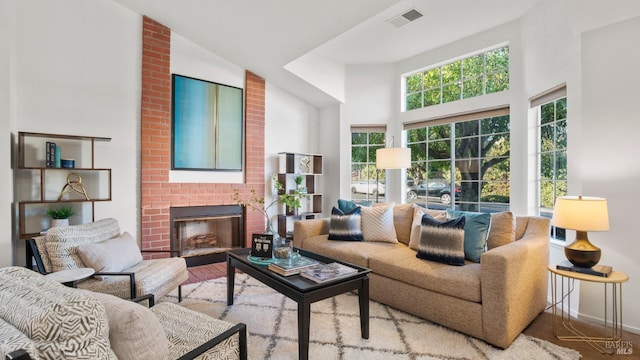 living room featuring a high ceiling, baseboards, a fireplace, and visible vents