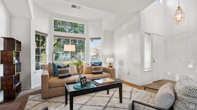 living room with a towering ceiling, baseboards, and visible vents