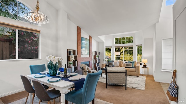 carpeted dining space featuring a chandelier, a brick fireplace, a towering ceiling, and baseboards