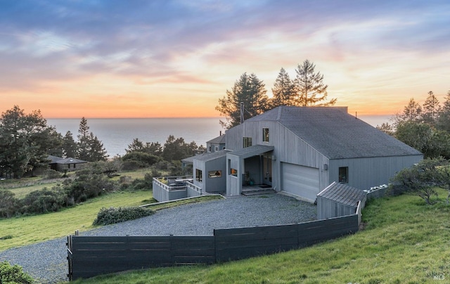 exterior space featuring driveway, a water view, a garage, and fence