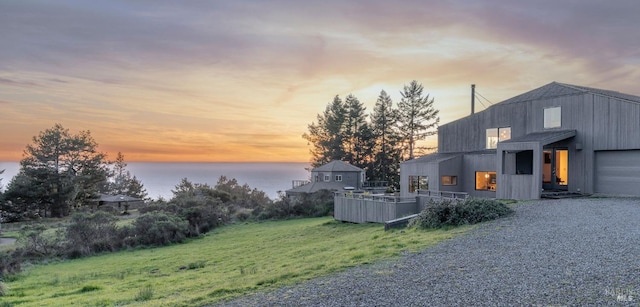 exterior space with a garage, a water view, and gravel driveway