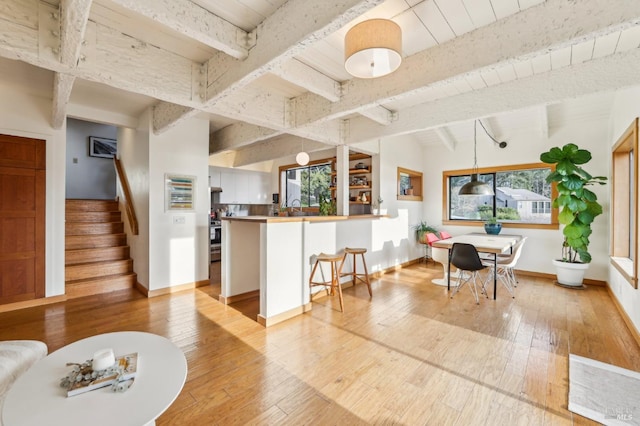 interior space featuring light hardwood / wood-style flooring, a kitchen breakfast bar, kitchen peninsula, pendant lighting, and white cabinets