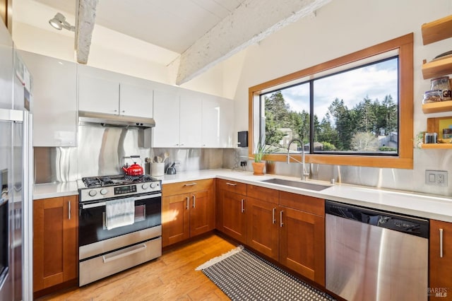 kitchen featuring under cabinet range hood, light countertops, appliances with stainless steel finishes, white cabinets, and a sink