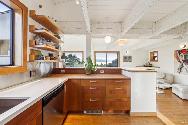 kitchen featuring beam ceiling, light countertops, light wood-type flooring, and stainless steel dishwasher