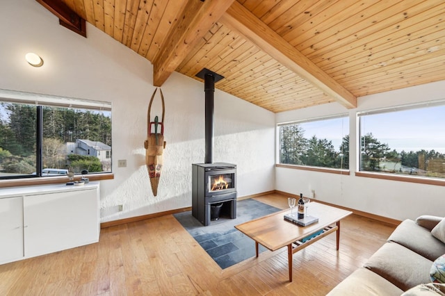 living area featuring a wood stove, vaulted ceiling with beams, wood finished floors, and baseboards