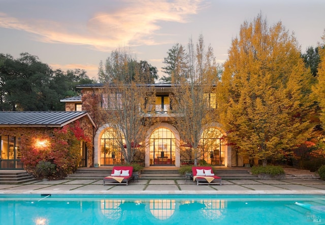 back house at dusk featuring a patio area