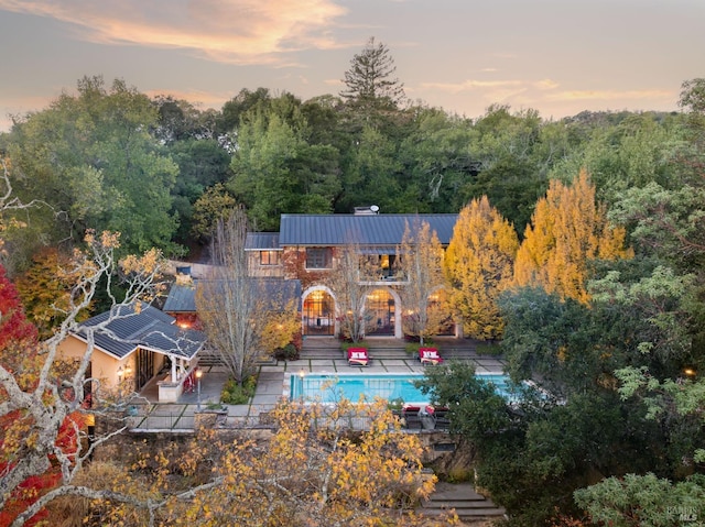 pool at dusk featuring a patio area and an outdoor pool