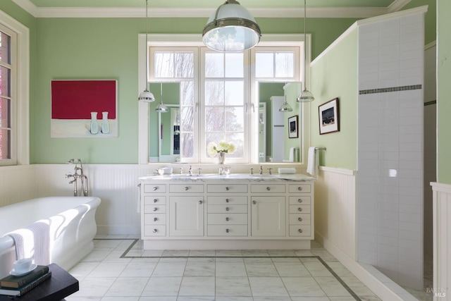 bathroom featuring double vanity, a wainscoted wall, a soaking tub, ornamental molding, and a sink