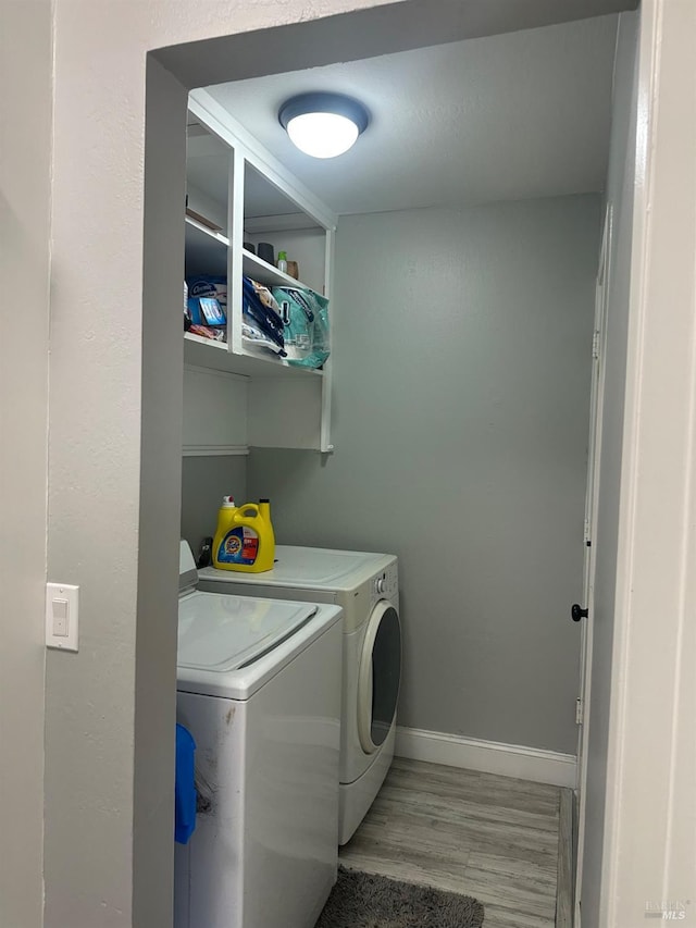 laundry area featuring independent washer and dryer and light hardwood / wood-style flooring