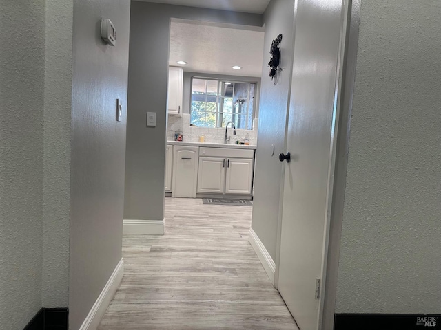 hallway with sink and light wood-type flooring