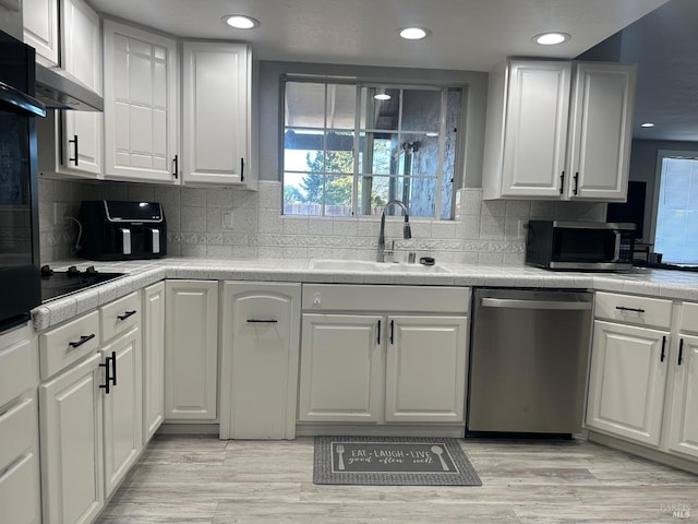 kitchen featuring appliances with stainless steel finishes, tasteful backsplash, white cabinetry, sink, and light hardwood / wood-style flooring