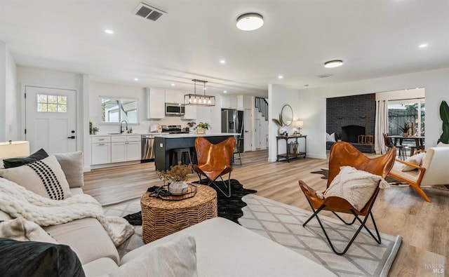 living room with sink, a wealth of natural light, a fireplace, and light hardwood / wood-style floors