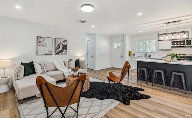 living room with light hardwood / wood-style floors and sink