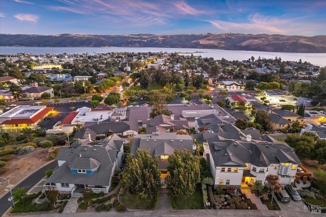 aerial view at dusk featuring a water and mountain view